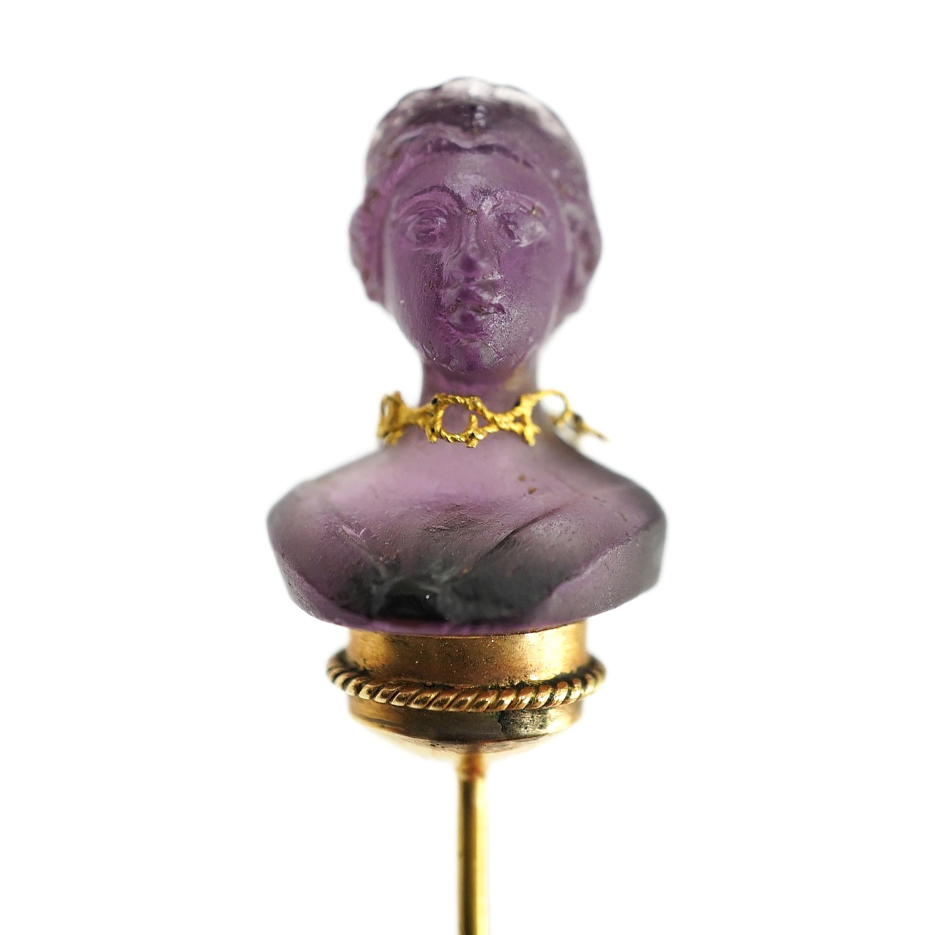 A 19th century French? gold and amethyst set stick pin, the stone carved as the bust of a lady, wearing a necklace